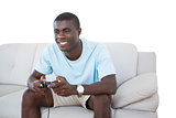 Smiling man sitting on couch playing video games