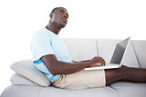 Thoughtful man sitting on couch using laptop