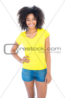 Pretty girl in yellow tshirt and denim hot pants smiling at camera
