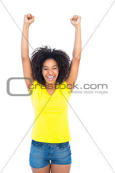 Pretty girl in yellow tshirt and denim hot pants cheering at camera