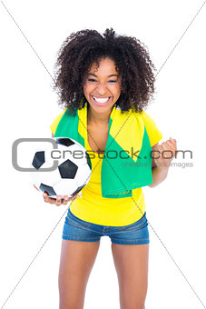 Pretty football fan holding brazilian flag cheering at camera