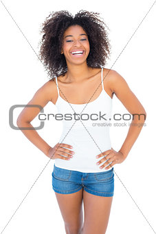 Pretty girl in white top and denim hot pants smiling at camera