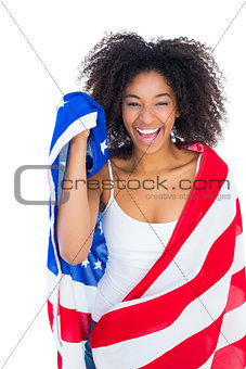 Pretty girl wrapped in american flag smiling at camera