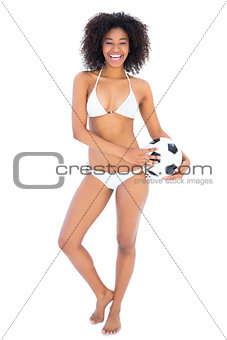 Smiling fit girl in white bikini holding football