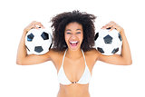 Excited fit girl in white bikini holding football