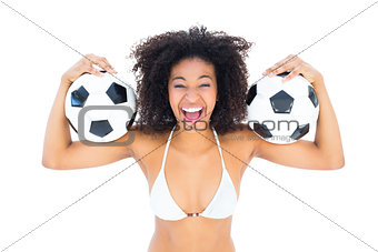 Excited fit girl in white bikini holding football