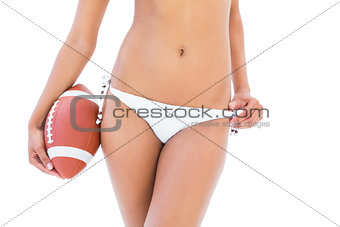 Fit girl in white bikini holding american football