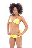 Slim girl in yellow bikini smiling at camera