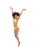 Fit girl in yellow bikini jumping and smiling at camera