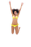 Fit girl in yellow bikini jumping and smiling at camera