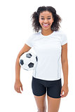 Pretty football fan in white holding ball smiling at camera