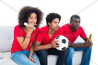 Nervous football fans in red sitting on couch