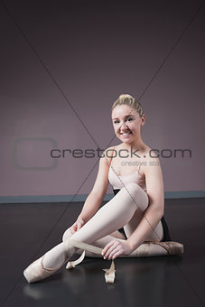 Pretty ballerina tying the ribbon on her ballet slippers