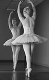 Graceful ballerina standing en pointe in front of mirror