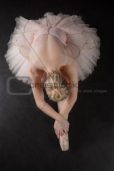 Graceful ballerina bending forward in pink tutu