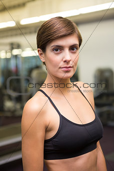 Fit brunette in black sports bra looking at camera