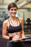 Fit trainer taking notes and smiling at camera