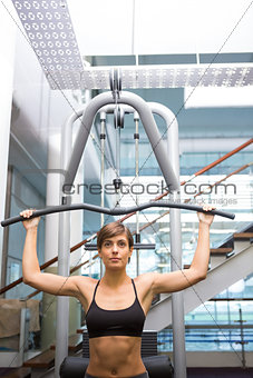 Fit brunette using weights machine for arms