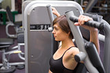 Athletic brunette using weights machine for arms