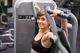 Happy brunette using weights machine for arms