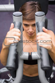 Serious brunette using weights machine for arms