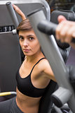 Serious brunette using weights machine for arms