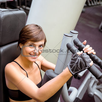 Focused brunette using weights machine for arms