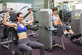 Healthy brunette using weights machine for arms