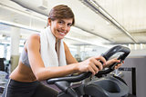 Fit smiling brunette working out on the exercise bike