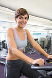 Smiling brunette working out on the cross trainer