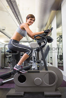 Fit smiling woman working out on the exercise bike