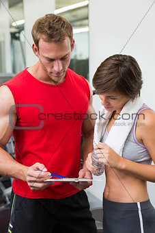 Handsome personal trainer with his client looking at clipboard