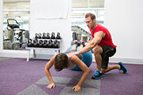 Personal trainer with client doing push up on exercise ball