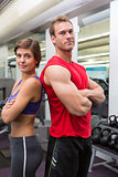 Fit attractive couple smiling at camera with arms crossed