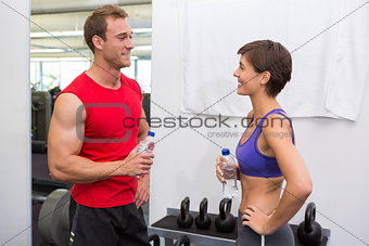 Fit attractive couple chatting holding water bottles