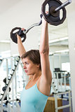 Fit brunette lifting heavy barbell over head