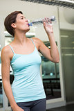 Fit brunette drinking from water bottle