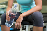 Fit woman sitting on bench holding water bottle