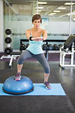 Fit brunette using bosu ball for squats