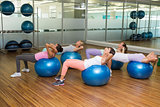 Fitness class doing sit ups on exercise balls in studio