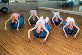 Fitness class stretching on exercise balls in studio