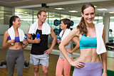 Fit woman smiling at camera in busy fitness studio