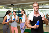 Fit man smiling at camera in busy fitness studio