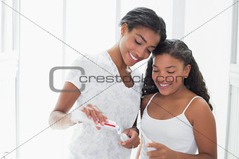 Pretty mother brushing her teeth with her daughter