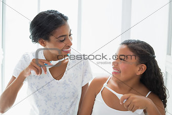 Pretty mother brushing her teeth with her daughter