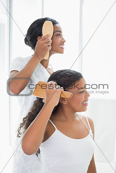 Mother and daughter brushing their hair together