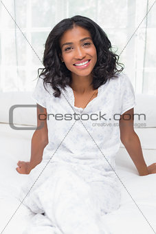Pretty woman smiling at camera sitting on bed
