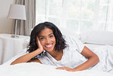 Pretty woman smiling at camera lying on bed