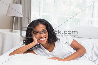Pretty woman smiling at camera lying on bed