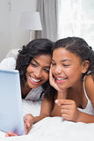 Happy mother and daughter using tablet together